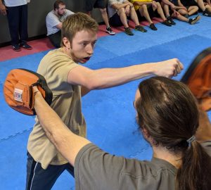A picture of a student hitting pads to show one of the drills taught at Krav Maga online training